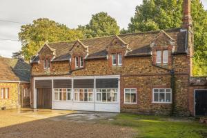 a large brick house with white garage doors at The Old Coach House C in Grimston