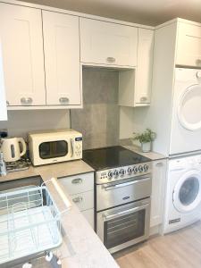 a kitchen with white cabinets and a dishwasher at The Studio @ Michael House in Horley