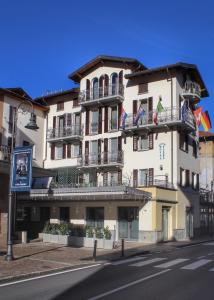 Un grand bâtiment blanc avec balcon se trouve dans une rue. dans l'établissement Hotel Avogadro, à San Pellegrino Terme
