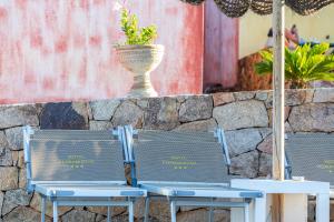2 Stühle und eine Vase an einer Steinmauer in der Unterkunft Hotel Pedra Niedda in Budoni