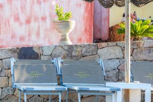 dos sillas y un jarrón en una pared de piedra en Hotel Pedra Niedda, en Budoni