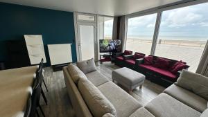 ミッデルケルケにあるZeedijk Westende 8p Appのビーチの景色を望むリビングルーム(ソファ、椅子付)