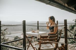 a woman sitting at a table drinking a cup of coffee at Zidanica Lackner in Črnomelj