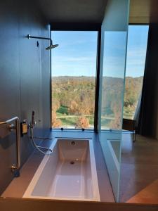 a bathroom with a tub with a large window at Cró Hotel Rural in Rapoula do Côa