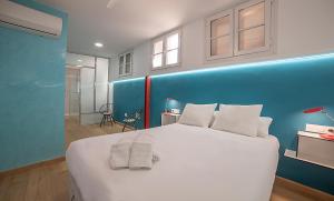 1 dormitorio con 1 cama blanca grande y pared azul en AlohaMundi Martínez Montañés en Sevilla