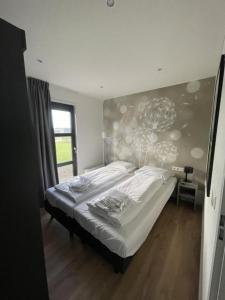 een slaapkamer met een bed in een kamer met een raam bij Chalet Sunrise Vierte Reihe Haus Nr 218 in Enkhuizen