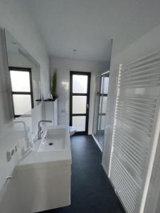 een witte badkamer met een wastafel en een spiegel bij Chalet Sunrise Vierte Reihe Haus Nr 218 in Enkhuizen