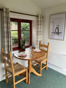 una mesa de madera y sillas en una habitación con ventana en Peaceful Open-Plan Cottage With A View, en Wellington