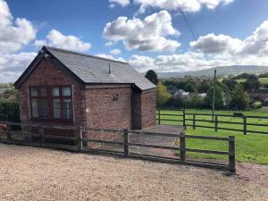 a small building in a field with a fence at Peaceful Open-Plan Cottage With A View in Wellington