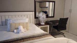 a bedroom with a bed and a desk with a fan at Tenlet guesthouse in Pretoria