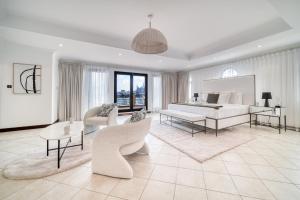 a white bedroom with a bed and a table and chairs at Frond D Villa, Palm Jumeirah - Mint Stay in Dubai