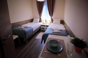 two beds in a small room with a table and a window at East Station Comfort Plus in Budapest