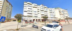 a white car parked in front of a large building at Panoramic Beach View Apartment (T2) in Caparica in Costa da Caparica