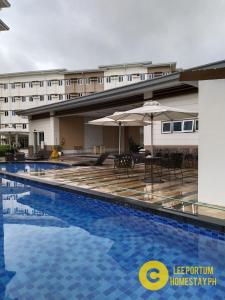 a hotel swimming pool with tables and umbrellas at C516 Place at SMDC Cheer Residences by Lee Portum in Marilao