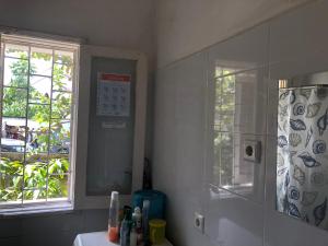 ein Bad mit einer Dusche, einem Waschbecken und einem Fenster in der Unterkunft Casa de Ferias in São Tomé