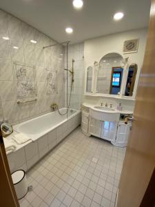 ein weißes Badezimmer mit einer Badewanne und einem Waschbecken in der Unterkunft VOLLMER home in Titisee-Neustadt