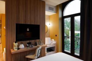 a bedroom with a bed and a tv and a window at La Maison des Bienheureux in Wasquehal