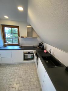 eine Küche mit weißen Schränken und einer schwarzen Arbeitsplatte in der Unterkunft VOLLMER home in Titisee-Neustadt
