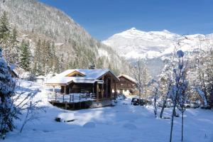 a log cabin in the snow with mountains in the background at Chalet L'Oratoire - Huge Garden - Renovated Historic Chalet with Mountain Views in Les Houches