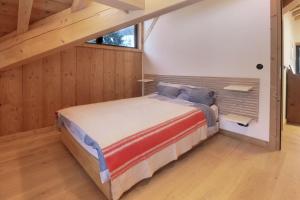 a bedroom with a bed in a room with wooden walls at Chalet L'Oratoire - Huge Garden - Renovated Historic Chalet with Mountain Views in Les Houches