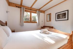 1 dormitorio con 1 cama blanca grande y ventana en Chalet Eveland - Proche du centre-ville - Calme en Les Houches