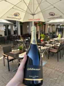 a person holding up a bottle of wine at Eifelstube Ahrweiler in Bad Neuenahr-Ahrweiler