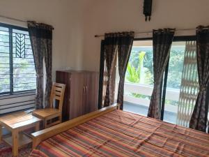 um quarto com uma cama, uma secretária e uma janela em Elim-A Sedate Nest em Santiniketan
