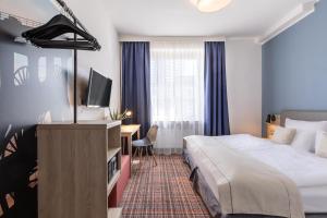 ein Hotelzimmer mit einem Bett und einem Schreibtisch in der Unterkunft theAmbassador Hotel I Essen City in Essen