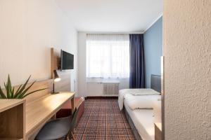 ein Hotelzimmer mit einem Bett und einem Schreibtisch in der Unterkunft theAmbassador Hotel I Essen City in Essen