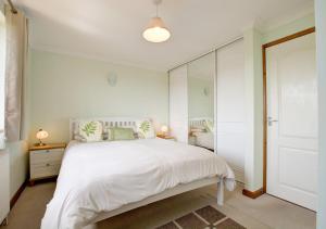 茅根海岸的住宿－The Buoys，卧室配有白色的床和镜子
