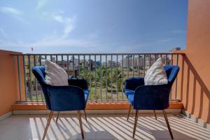 two blue chairs sitting on a balcony with a view at Premium 2BHK -10 min to GOI airport & beach -Pool access -Balcony with city view in Dabolim