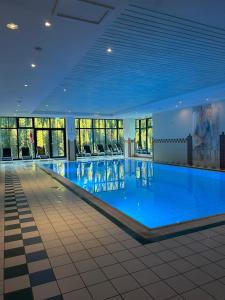 a large swimming pool with blue water in a building at Kinder- und Familienhotel Nockalm in Innerkrems