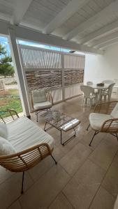 eine Terrasse mit Stühlen, einem Tisch und Stühlen in der Unterkunft Dimora Arnesano in Torre Lapillo