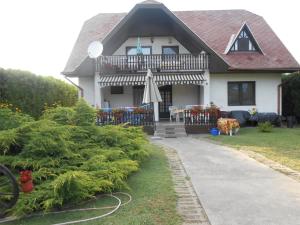 ein Haus mit einer Veranda und einem Balkon mit einer Terrasse in der Unterkunft Simon Apartmanház Zamárdi in Zamárdi