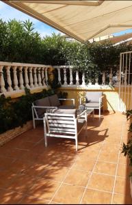 eine Terrasse mit zwei Bänken und einem Sonnenschirm in der Unterkunft Adosado/casa con terraza y buhardilla. Playa El Perelló in El Perelló