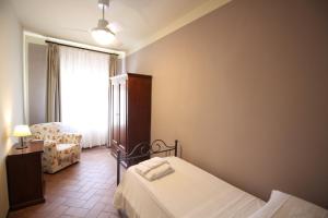 a bedroom with a bed and a chair and a window at Agriturismo Casale Dello Sparviero in Castellina in Chianti