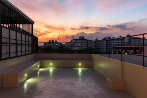 a rooftop patio with a sunset in the background at The STYLISH Hometel Sukhumvit in Bangkok