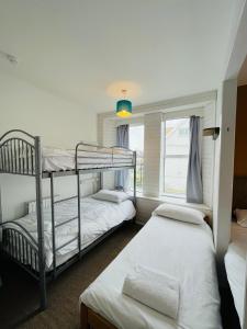 two bunk beds in a room with a window at Elemental Surf Lodge in Newquay