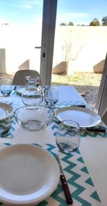 una mesa con platos y vasos encima en Dúplex con patio y parrilla en Terrazas del Sol en Neuquén