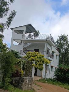 ein großes weißes Gebäude mit einem Balkon und Bäumen in der Unterkunft Sushmika Home in Yercaud