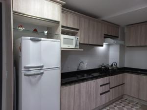 a kitchen with a white refrigerator and a microwave at Loft torres praia da Cal in Torres