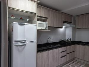 a kitchen with a white refrigerator and a microwave at Loft torres Las piedras praia da Cal in Torres
