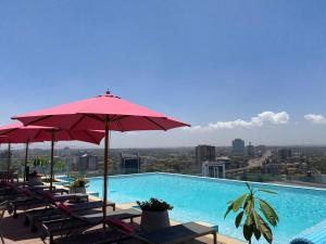 a pool with chairs and umbrellas on top of a building at Spacious 1 bedroom Apt at Skynest (709) in Nairobi