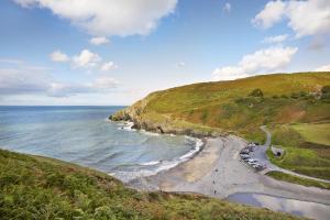 a group of cars parked on a beach next to the ocean at Y Cartws near Llangrannog in Llangrannog