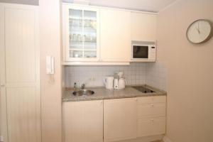 eine weiße Küche mit einer Spüle und einer Mikrowelle in der Unterkunft Strandstraße 32 - Wohnung 27 / 579 in Kühlungsborn