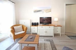 ein Wohnzimmer mit einem TV, einem Stuhl und einem Tisch in der Unterkunft Strandstraße 32 - Wohnung 27 / 579 in Kühlungsborn