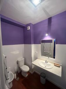 a purple and white bathroom with a toilet and a sink at Orquídea Real in Villablino