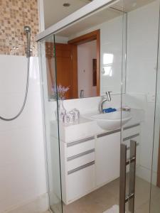 La salle de bains est pourvue d'un lavabo et d'une douche. dans l'établissement RICARDO Pousada Q1 Suíte, à Vila Velha