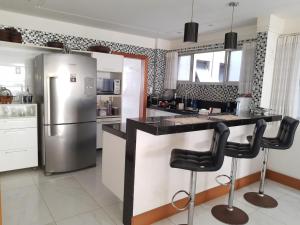 uma cozinha com um frigorífico e 2 bancos de bar em RICARDO Pousada Q1 Suíte em Vila Velha