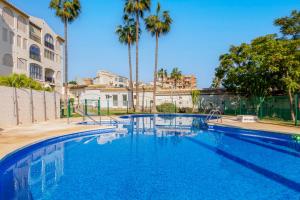 a swimming pool with palm trees and a building at Imperial Puerto 2 4B By IVI Real Estate in Torremolinos